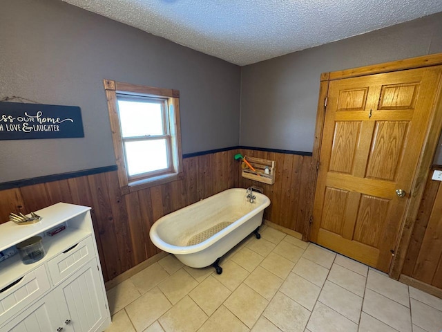 bathroom with a soaking tub, a wainscoted wall, a textured ceiling, and wood walls