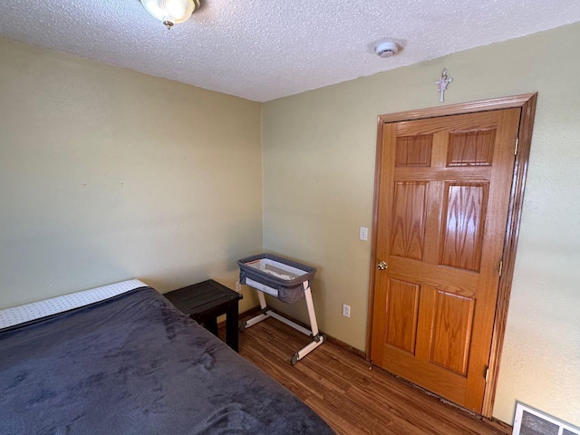 unfurnished bedroom with a textured ceiling, wood finished floors, and visible vents