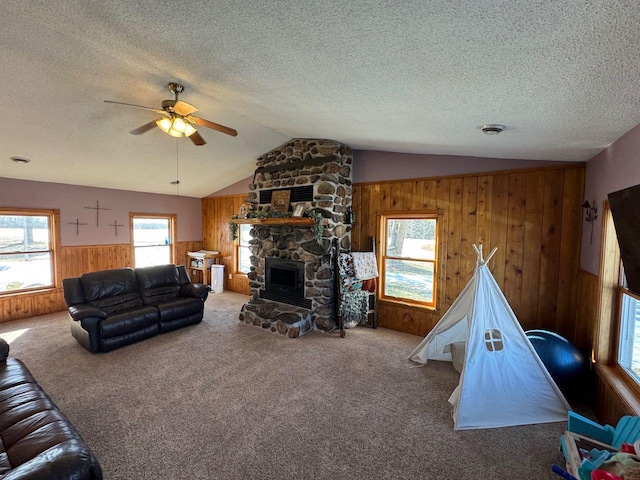 carpeted living area featuring lofted ceiling, a textured ceiling, wood walls, a fireplace, and visible vents