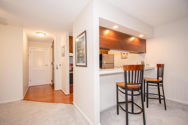 corridor with recessed lighting, light colored carpet, and baseboards