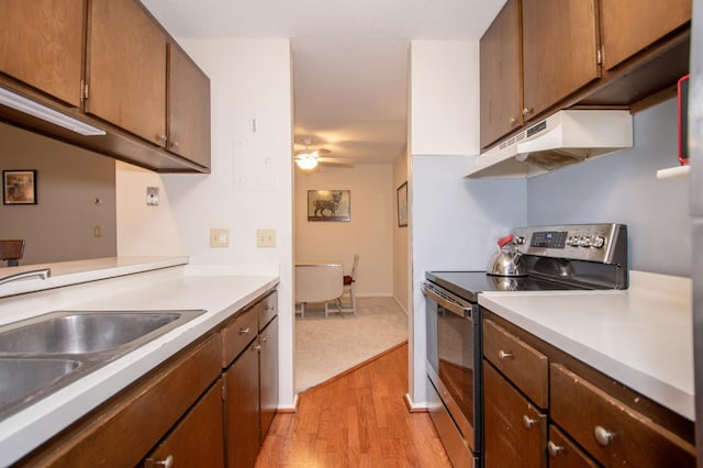 kitchen with under cabinet range hood, ceiling fan, stainless steel electric range, and light countertops