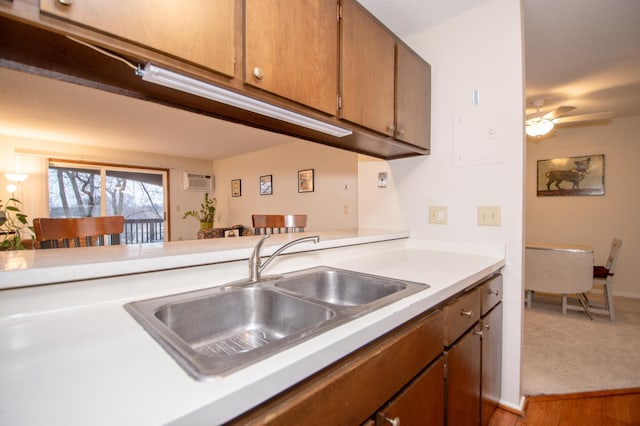 kitchen with ceiling fan, wood finished floors, a wall mounted air conditioner, light countertops, and a sink