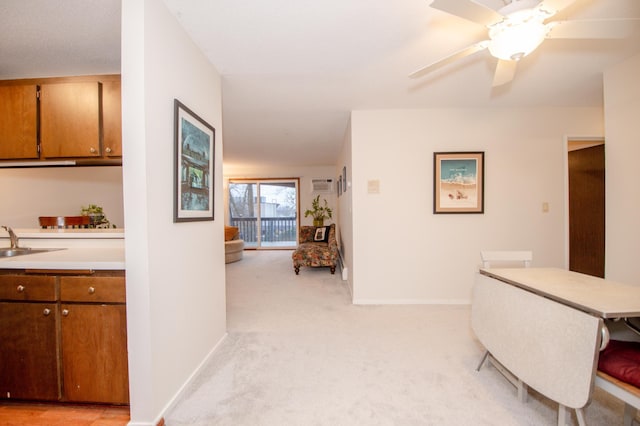 hallway featuring light carpet, a sink, and baseboards