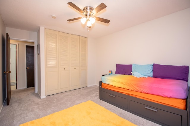 bedroom with a ceiling fan, baseboards, a closet, and light colored carpet