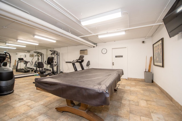 recreation room featuring stone finish floor, pool table, an AC wall unit, and baseboards