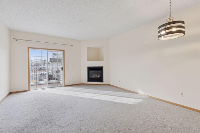 unfurnished living room featuring a glass covered fireplace, light colored carpet, baseboards, and a textured ceiling