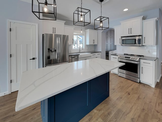 kitchen with stainless steel appliances, backsplash, light wood-type flooring, and a sink