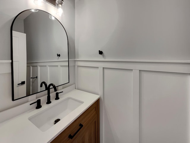 bathroom featuring a wainscoted wall, a decorative wall, and vanity