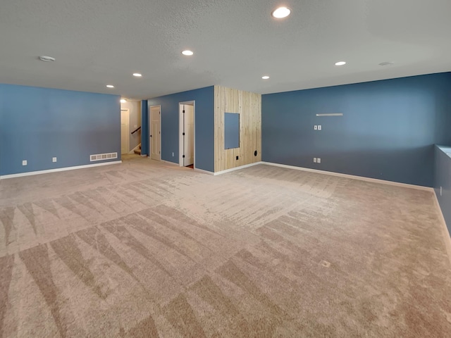 empty room featuring carpet floors, recessed lighting, visible vents, stairway, and baseboards