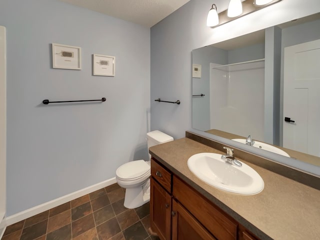 bathroom featuring baseboards, vanity, toilet, and walk in shower