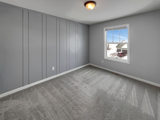 carpeted spare room with baseboards, visible vents, and a textured ceiling