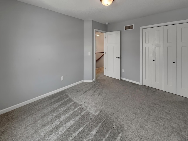 unfurnished bedroom featuring a closet, carpet flooring, visible vents, and baseboards