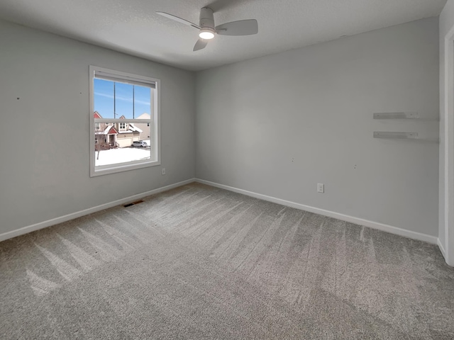 carpeted empty room featuring ceiling fan, a textured ceiling, visible vents, and baseboards