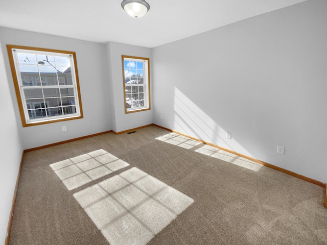 empty room featuring carpet, visible vents, and baseboards