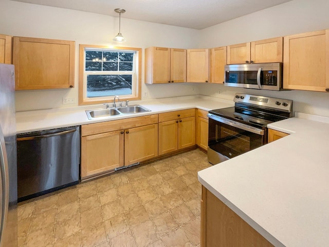 kitchen featuring light brown cabinets, stainless steel appliances, a sink, light countertops, and decorative light fixtures