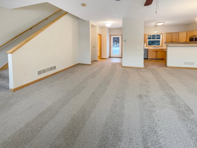 unfurnished living room with visible vents, ceiling fan, and light carpet