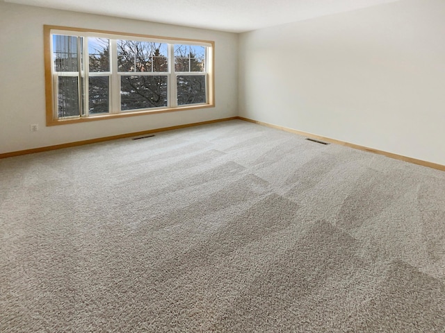 carpeted spare room featuring baseboards and visible vents