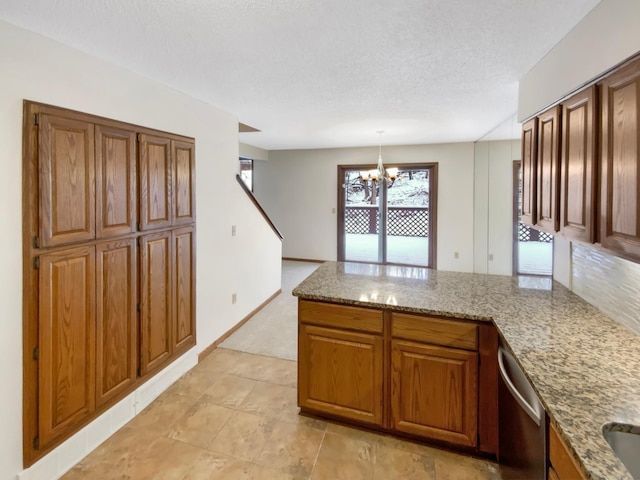 kitchen with a notable chandelier, a peninsula, light stone countertops, dishwasher, and brown cabinetry