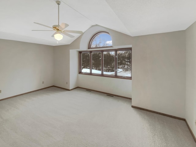 spare room featuring lofted ceiling, visible vents, carpet flooring, ceiling fan, and baseboards