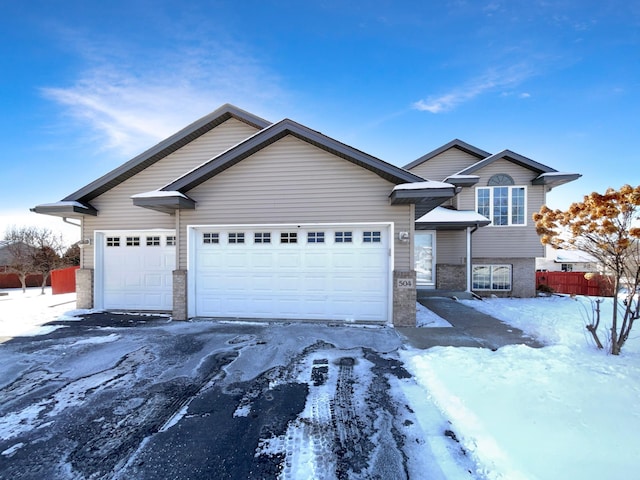 view of front of home with a garage, brick siding, and fence