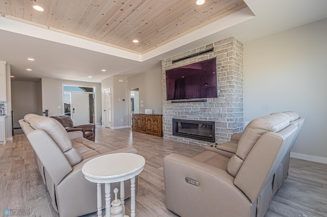 living room with a tray ceiling, wooden ceiling, light wood finished floors, and baseboards