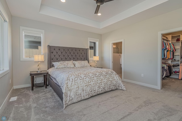 bedroom featuring carpet floors, a walk in closet, and a raised ceiling