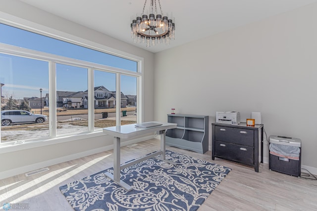 home office featuring plenty of natural light, visible vents, a notable chandelier, and wood finished floors