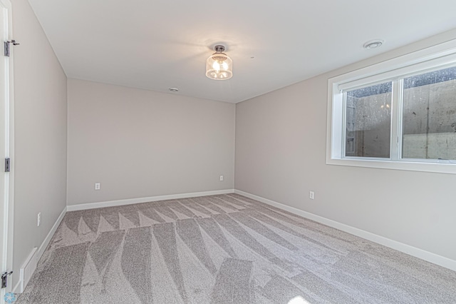 spare room featuring light carpet and baseboards