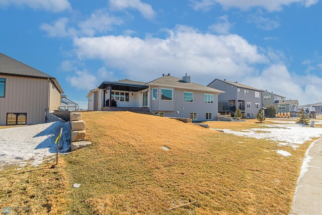 back of property featuring a yard and a residential view