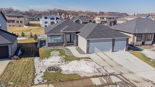 view of front of property with brick siding, roof with shingles, a garage, a residential view, and driveway