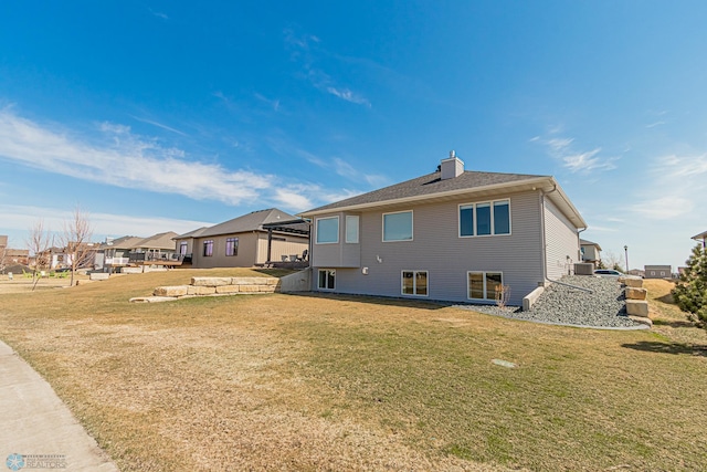 back of house featuring a lawn, a chimney, central AC, and a residential view