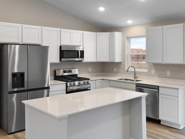 kitchen with a center island, lofted ceiling, light countertops, appliances with stainless steel finishes, and a sink