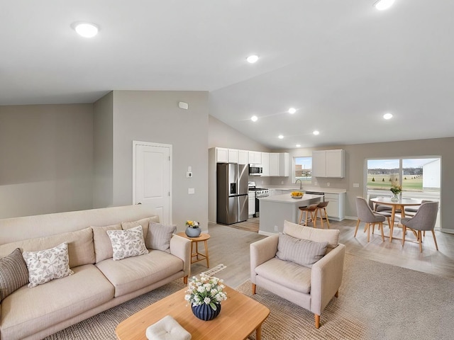 living area with light wood-style floors, high vaulted ceiling, and recessed lighting