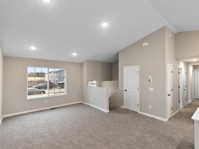 carpeted spare room with lofted ceiling, visible vents, baseboards, and recessed lighting