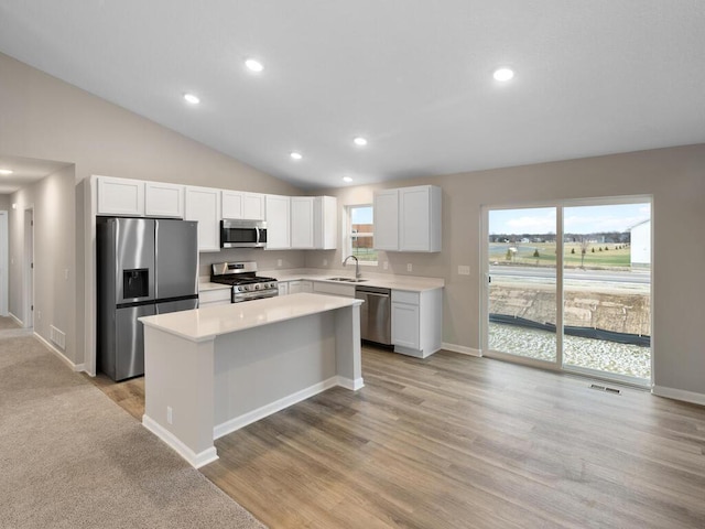 kitchen with white cabinets, a kitchen island, stainless steel appliances, light countertops, and a sink