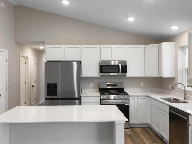 kitchen featuring lofted ceiling, a sink, white cabinets, light countertops, and appliances with stainless steel finishes