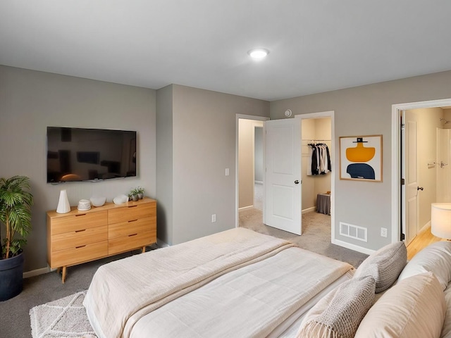 bedroom with baseboards, visible vents, connected bathroom, a spacious closet, and carpet floors