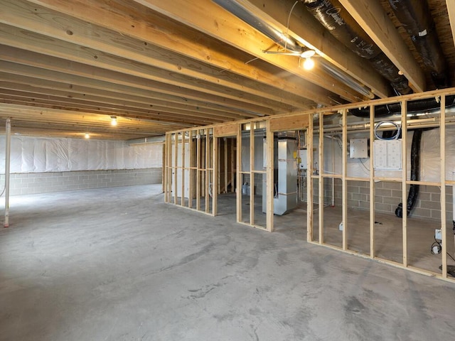 unfinished basement featuring electric panel and fridge