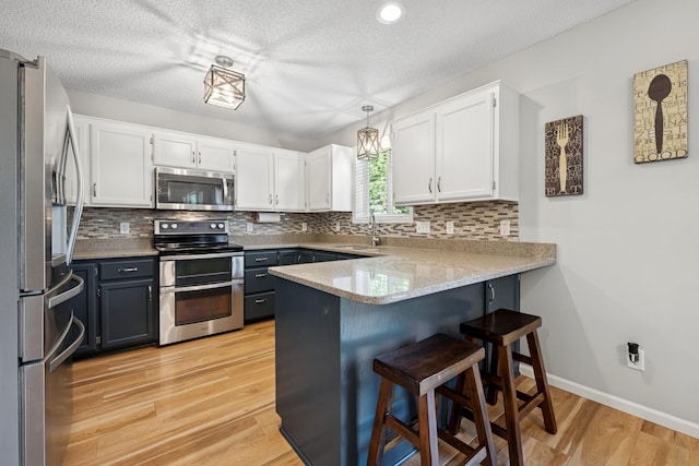 4514 Mcallister Ave NE, Saint Michael, MN 55376 - kitchen featuring appliances with stainless steel finishes, a peninsula, a sink, white cabinets, and a breakfast bar area