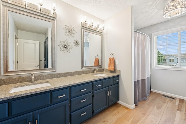 4514 Mcallister Ave NE, Saint Michael, MN 55376 - bathroom with wood finished floors, a textured ceiling, double vanity, baseboards, and curtained shower