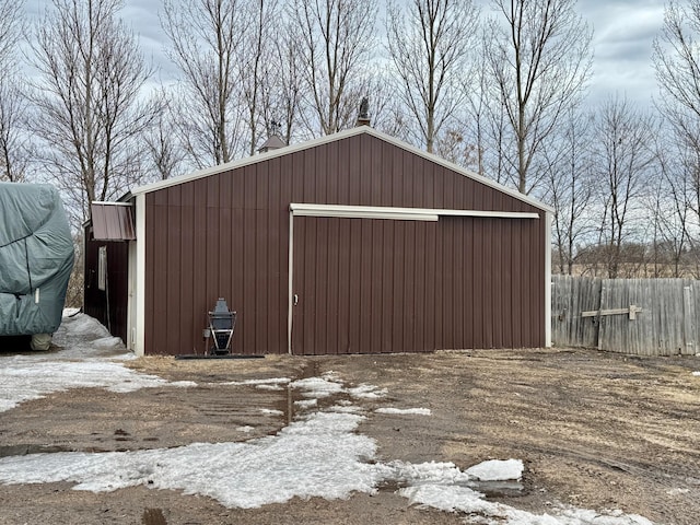 snow covered garage with a garage and fence