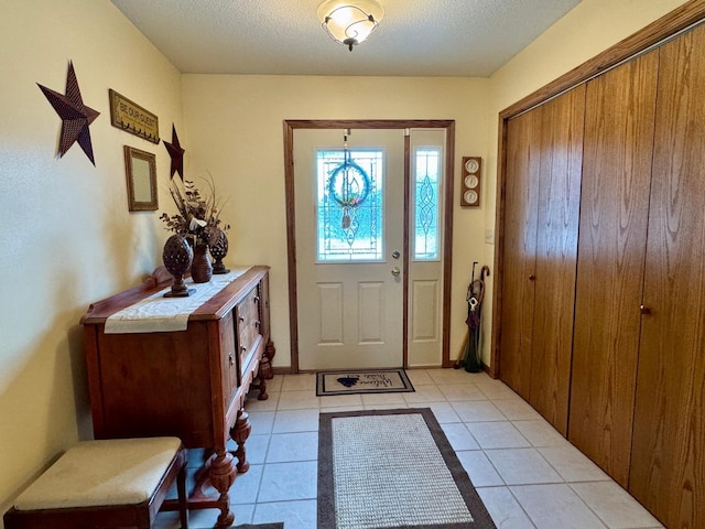 entryway with a textured ceiling and light tile patterned floors