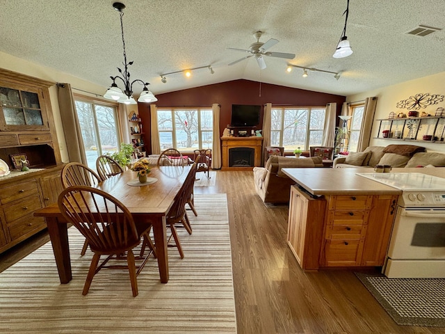 kitchen featuring lofted ceiling, white electric range, a fireplace, visible vents, and light wood-style floors