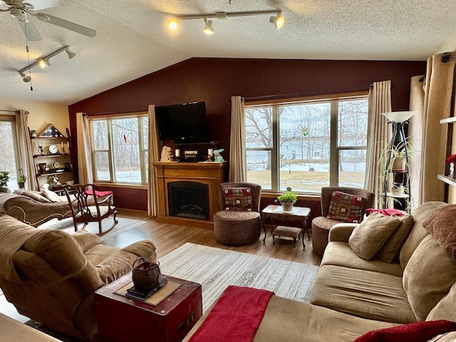 living room with vaulted ceiling, a textured ceiling, a fireplace, and wood finished floors