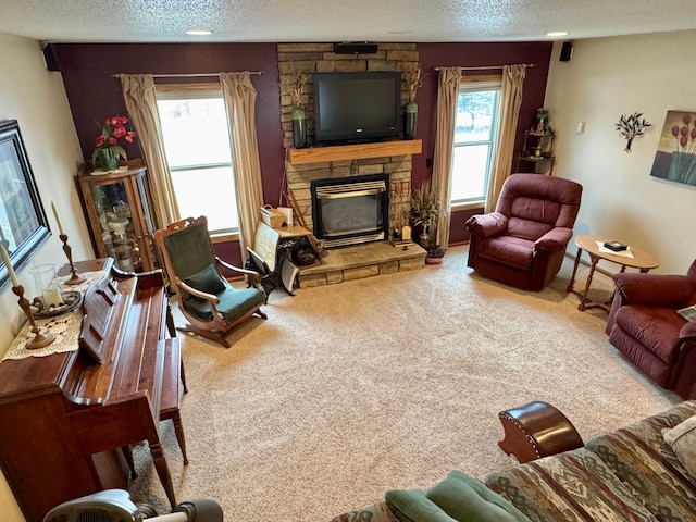 living area with a textured ceiling, a fireplace, a wealth of natural light, and carpet flooring