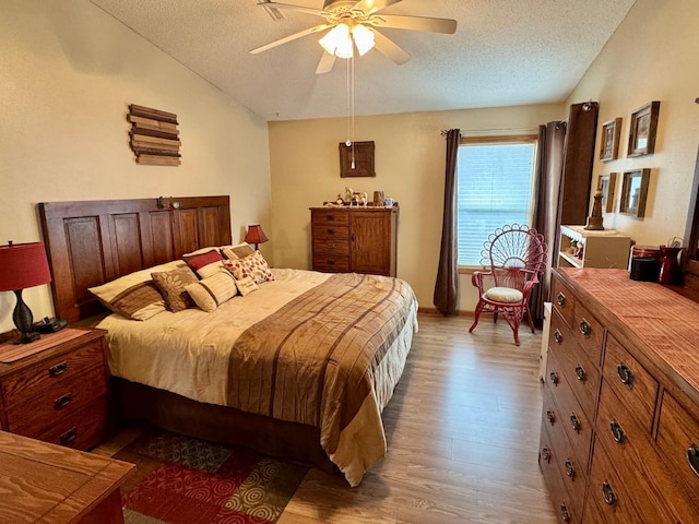 bedroom with a textured ceiling, baseboards, a ceiling fan, and light wood-style floors