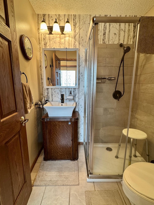 bathroom featuring toilet, wallpapered walls, vanity, and a stall shower