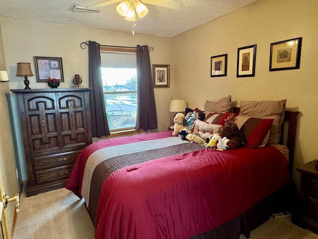 carpeted bedroom featuring a textured ceiling, ceiling fan, and visible vents