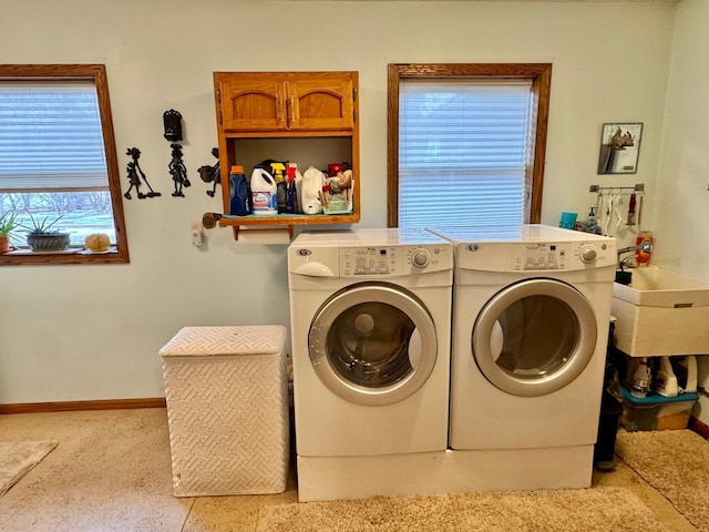 washroom featuring cabinet space, baseboards, and separate washer and dryer