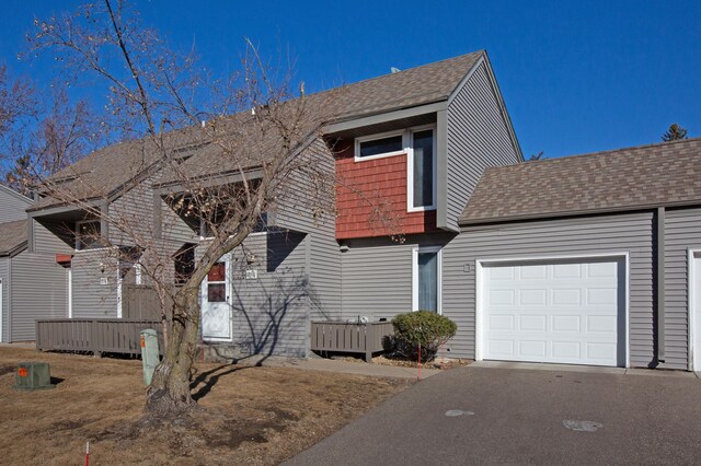 view of front of house with an attached garage, aphalt driveway, and roof with shingles